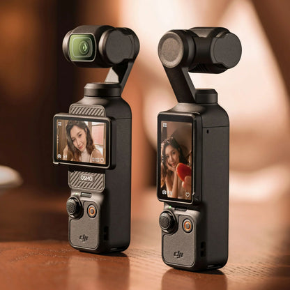 Two handheld DJI Osmo Pocket cameras on a table, each displaying a selfie on the screen.