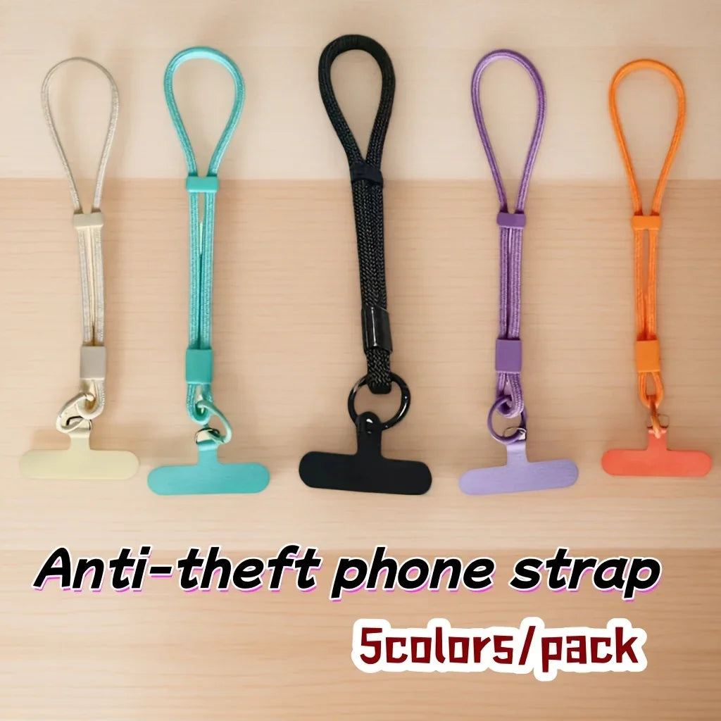 Five anti-theft phone straps in beige, turquoise, black, purple, and orange on a wooden surface.
