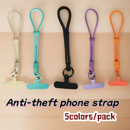 Five anti-theft phone straps in beige, turquoise, black, purple, and orange on a wooden surface.